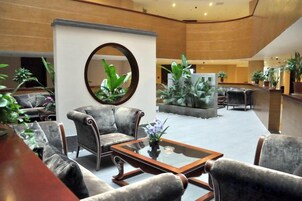 Un hall con disposición de asientos, una mesa de centro y un espejo grande.