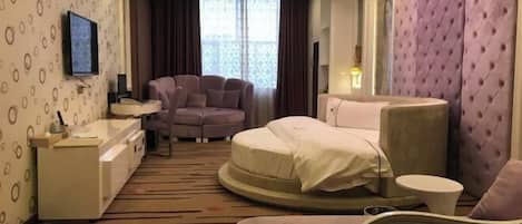 A hotel room with a bed, a sofa, a desk, and a TV.