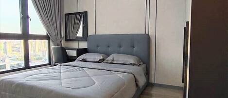 A bedroom with a large bed, a ceiling fan, a nightstand, and a window with curtains.