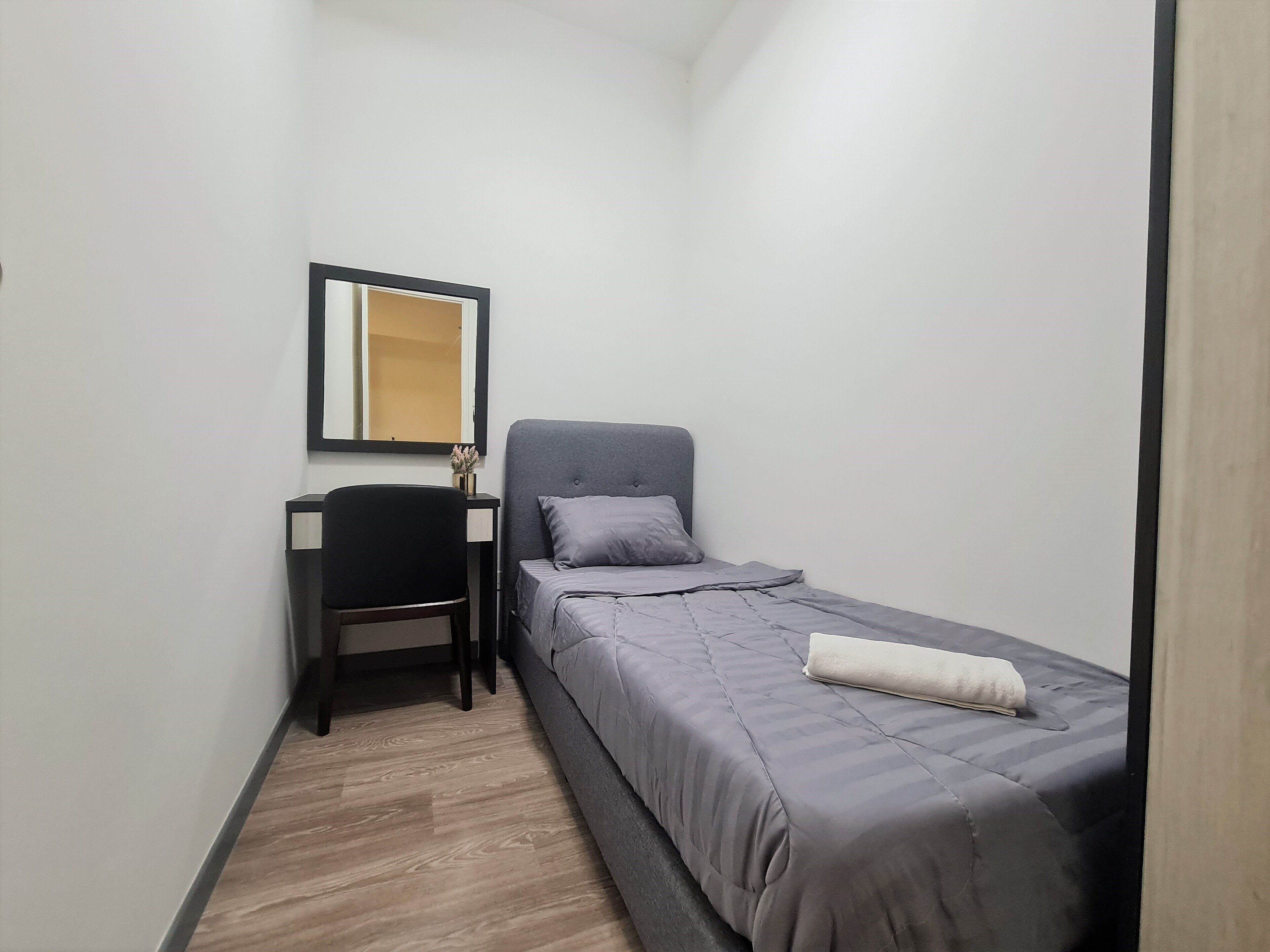 Un dormitorio pequeño y ordenado, con cama, escritorio y silla.