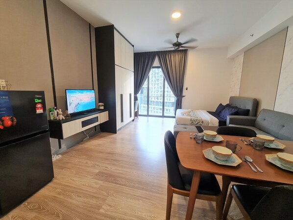 Una sala moderna con televisor de pantalla plana, mesa de comedor con platos y cubiertos, y un ventilador de techo.