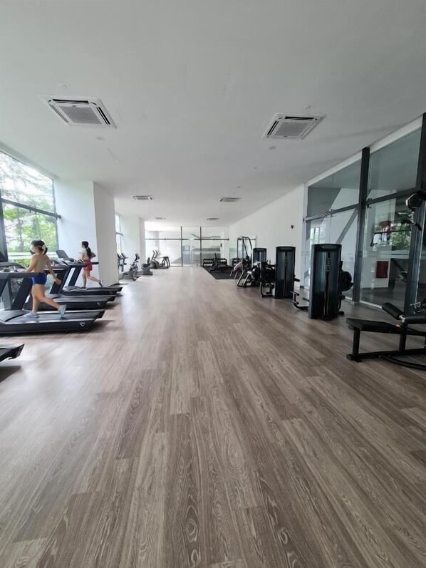 Een ruime fitnessruimte met loopbanden, elliptische trainers en gewichten.
