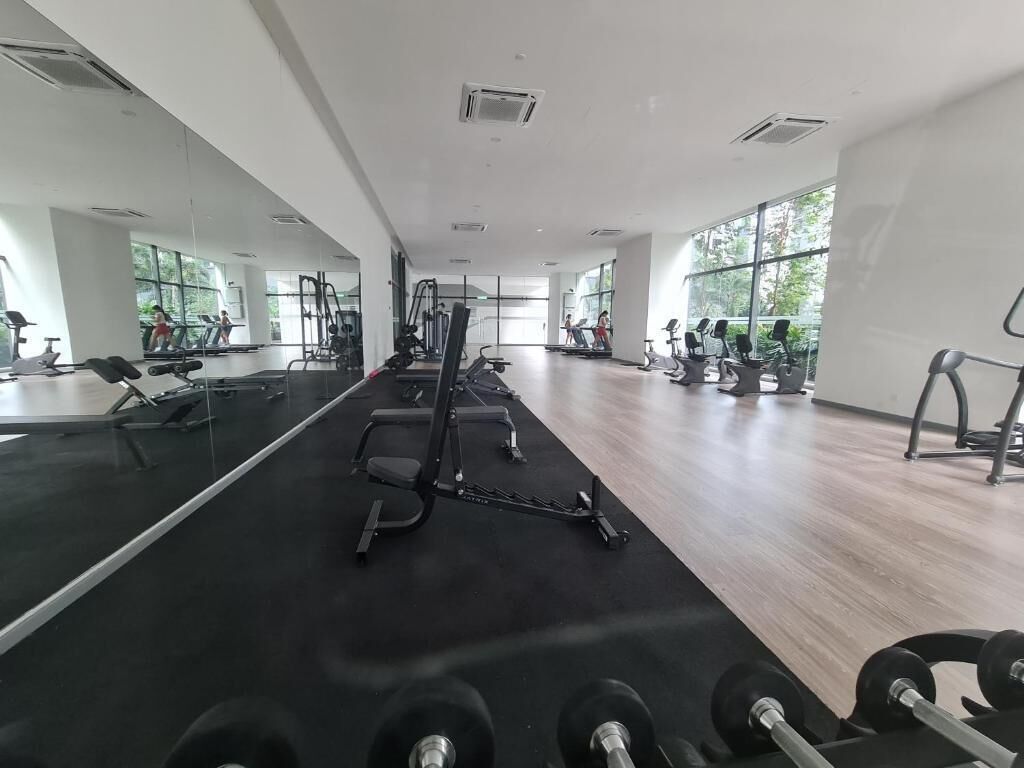 A gym with exercise equipment, mirrors, and large windows.
