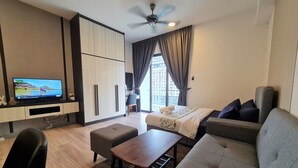 A modern hotel room with a flat-screen TV, a sofa, a coffee table, and a desk. - Southlink Lifestyle Apartment Bangsar (Kuala Lumpur)