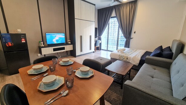A modern hotel room with a dining area, a sofa, a TV, and a balcony with a view. - Southlink Lifestyle Apartment Bangsar (Kuala Lumpur)