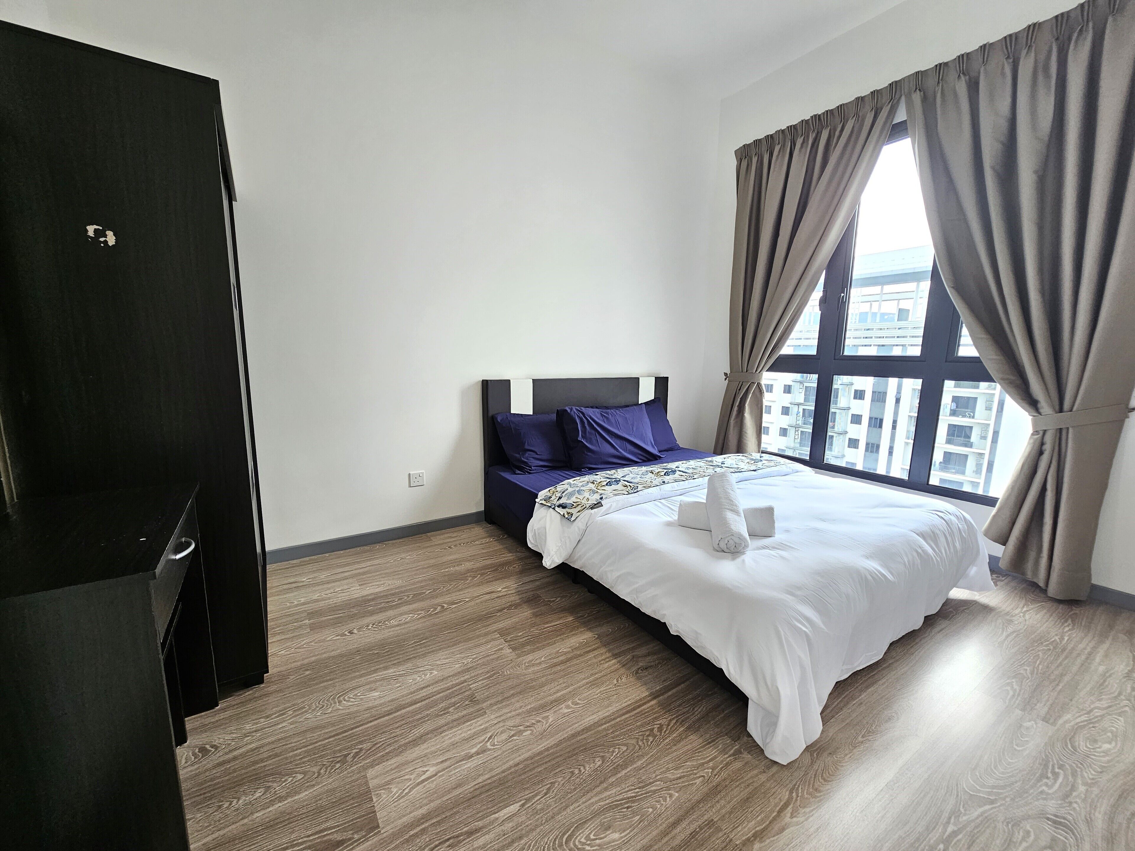 Une chambre d’hôtel avec un lit, une armoire et une fenêtre avec des rideaux.