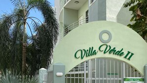 Villa Verde II met een toegangspoort, palmbomen en een heldere lucht.