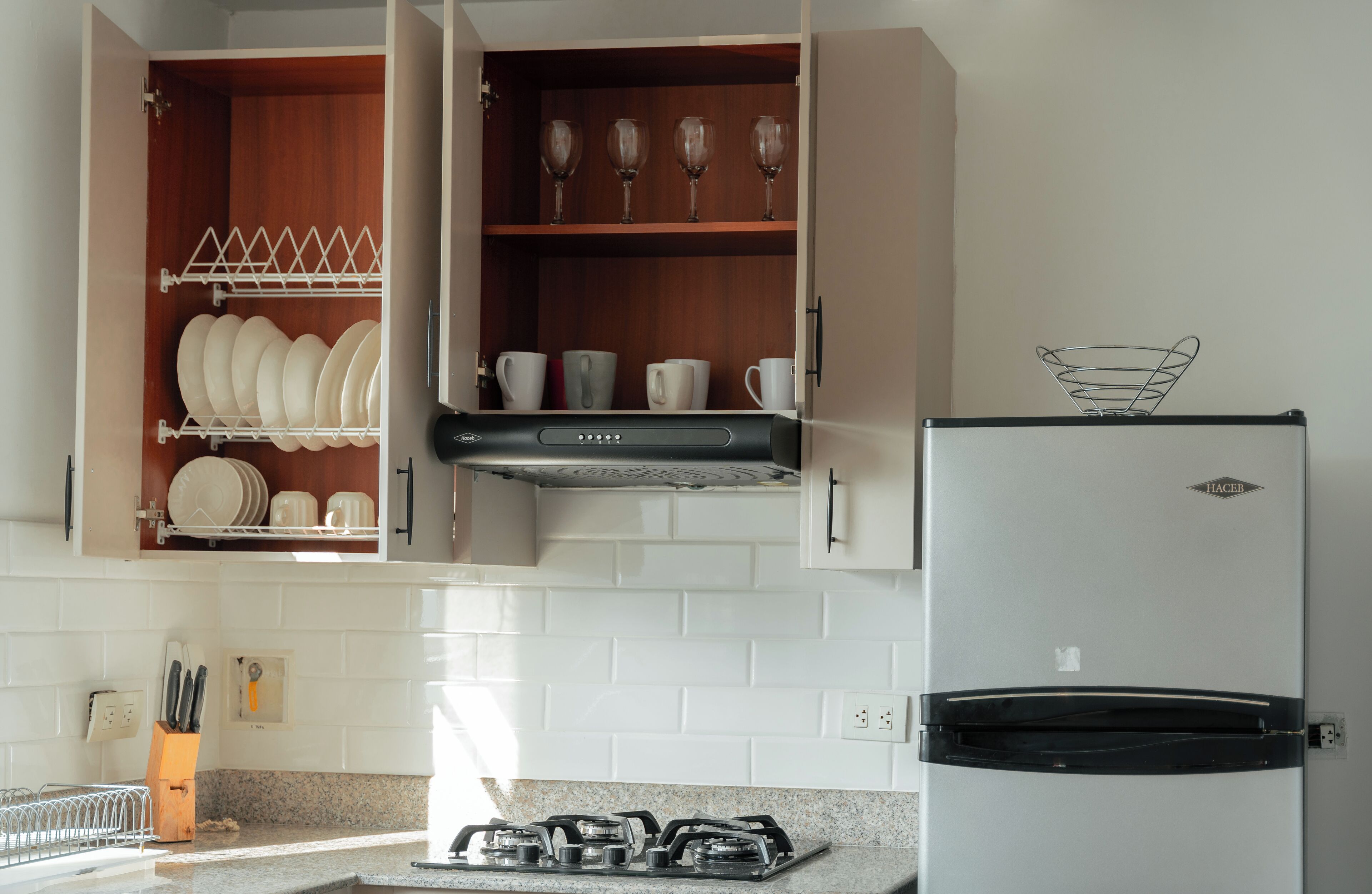 Cucina con mobili bianchi, frigorifero in acciaio inossidabile e piano cottura a gas.