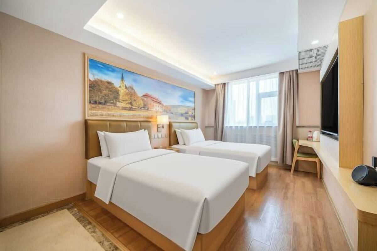 A hotel room with two beds, a desk, a TV, and a painting on the wall.