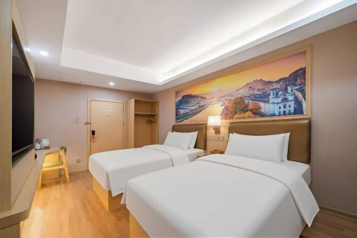 A hotel room with two beds, a television, a painting on the wall, and a small table with a chair.