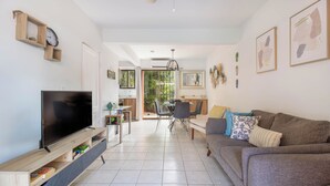 Ein modernes Wohnzimmer mit einem Flachbildfernseher, einem grauen Sofa und einem Essbereich mit Tisch und Stühlen.