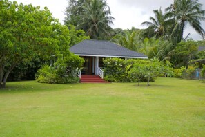 Situated in a lush garden, this charming residence features a simple white exterior and a cozy porch.
