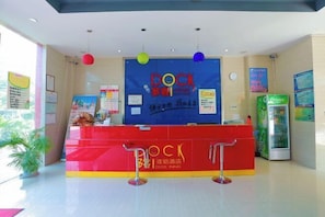 A reception area with a red counter, 'DOCK' signage, and a green vending machine. - Duoke Chain Hotel (Mengla)