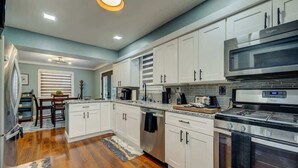 Una cocina moderna con gabinetes blancos, electrodomésticos de acero inoxidable y piso de madera.