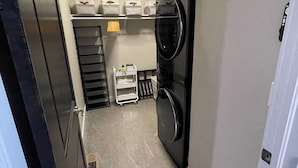 Une buanderie équipée d’un lave-linge, d’un sèche-linge, d’un luminaire au plafond et d’étagères de rangement.