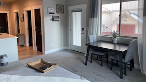 Un salon moderne comprenant un coin repas, un ventilateur de plafond, une grande fenêtre avec des rideaux et un panneau d’accueil.