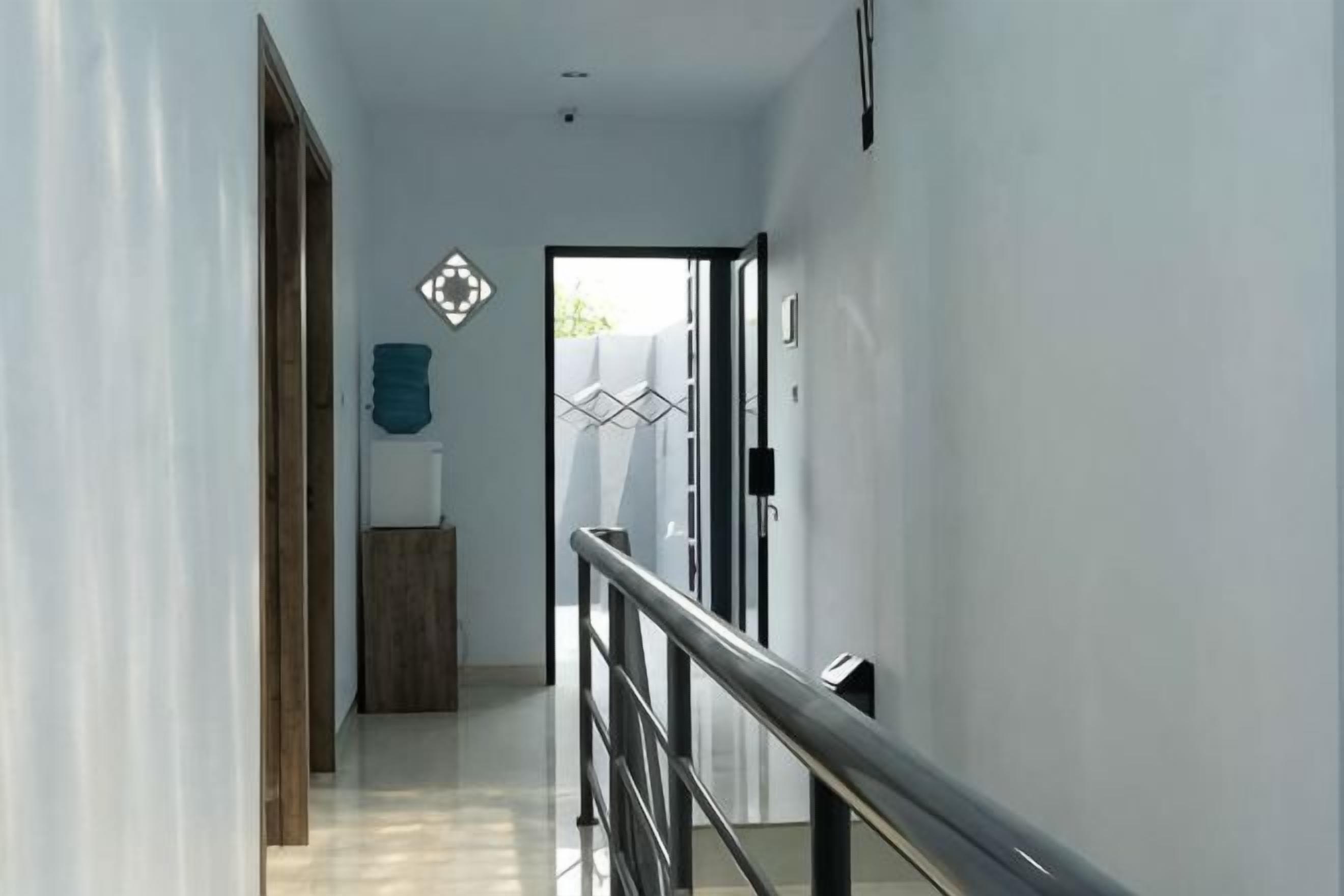 A hallway with a wooden door, a metal railing, and a geometric wall decoration.