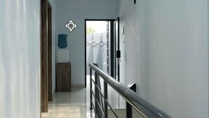 Um corredor com porta de madeira, corrimão de metal e decoração geométrica na parede.
