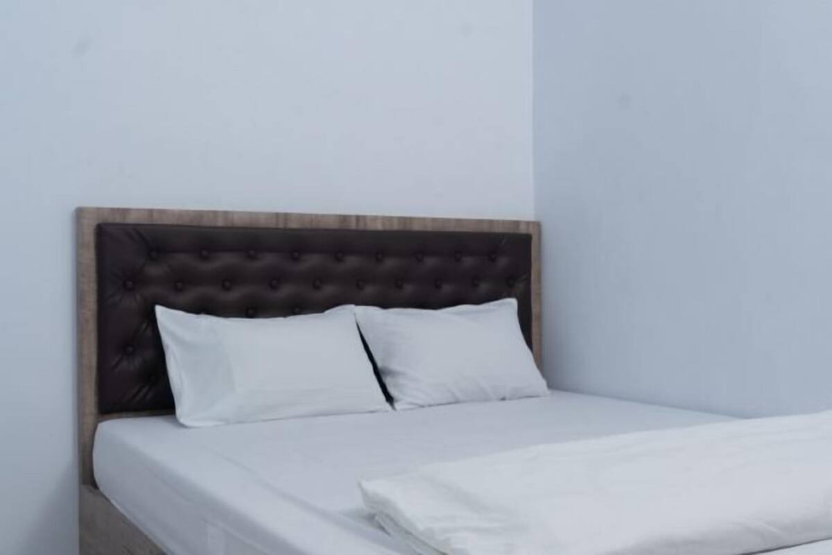 A bed with a tufted headboard, white bedding, and a wooden frame.