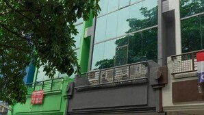 A multi-story building with a green facade, large windows, and a balcony with a metal railing. - Hotel Padma Tangerang (Karawaci)