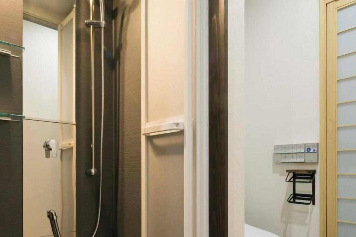 Un baño con ducha, toallero y enchufe de pared.