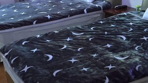 Two twin beds with star and crescent patterns, a bedside table, and a nightstand with a lamp. - Longwangshan Huanle Inn (Anji)