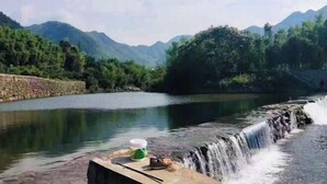 Un río con una cascada, rodeado de montañas y árboles.