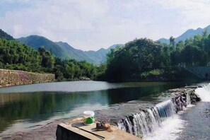 A river with a waterfall, surrounded by mountains and trees. - Longwangshan Huanle Inn (Anji)