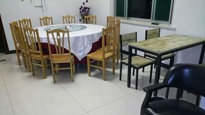A dining area with a round table, wooden chairs, and a black chair. - Longwangshan Huanle Inn (Anji)