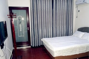 A hotel room with a bed, a door with a frosted glass panel, and a curtain. - Longwangshan Huanle Inn (Anji)
