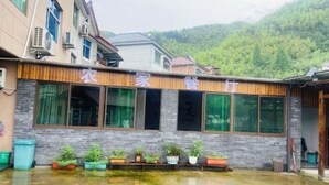 Un edificio con un letrero que dice "YI JIAO" y una fila de plantas en macetas al frente.