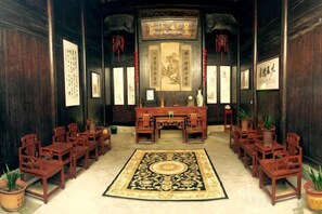 Une salle à l’ancienne, dotée d’un bureau central, de plusieurs chaises et d’un grand tapis à motifs.