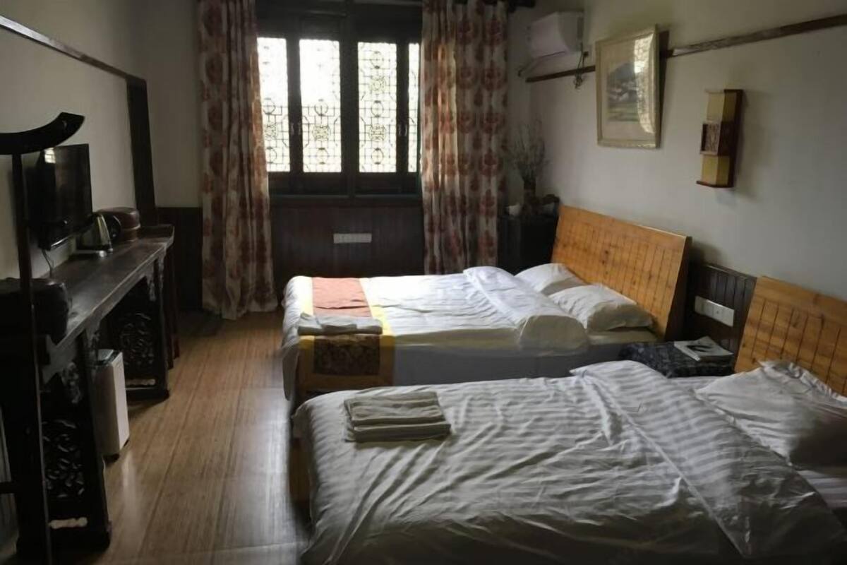 A hotel room with two beds, a desk with a television, and a window with curtains.