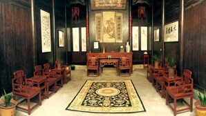 A traditional room with wooden furniture, a central desk, and framed calligraphy on the walls. - Dongli Yashe Hotel (Jing County)