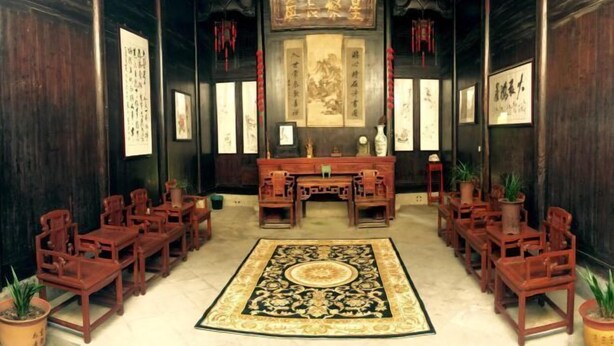 A traditional room with wooden furniture, a central desk, and framed calligraphy on the walls. - Dongli Yashe Hotel (Jing County)