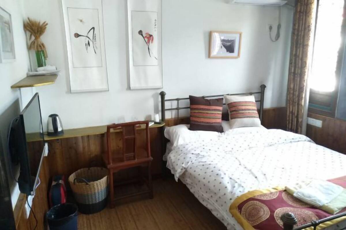 A bedroom with a bed, a chair, a desk, and a television.