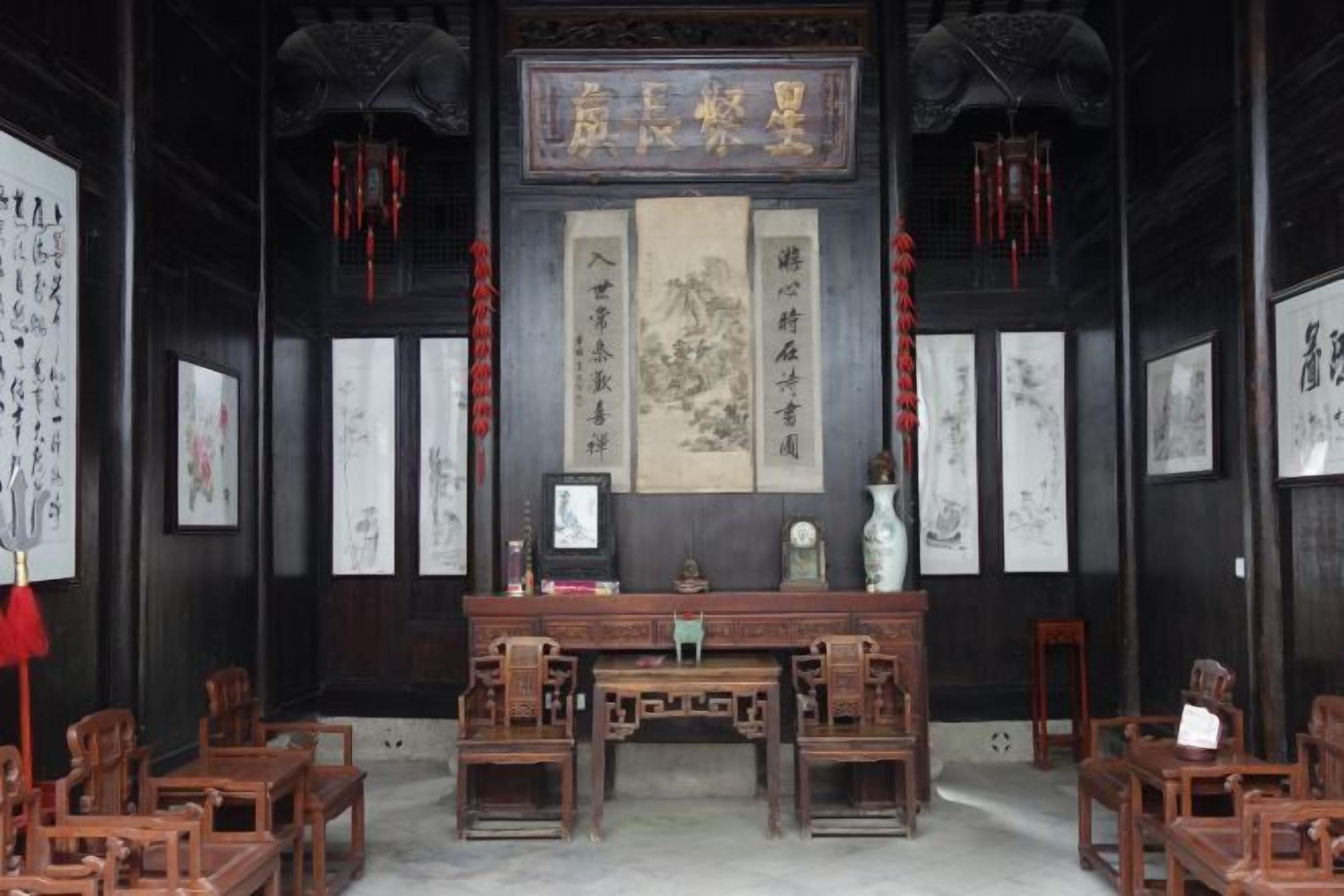 A traditional room with a wooden desk, chairs, and calligraphy on the walls.