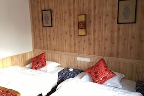 Une chambre avec deux lits, des lambris en bois sur les murs et deux tableaux encadrés.