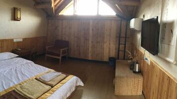 A room with a bed, a chair, a television, and a window.