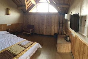 Una habitación con cama, sillón, televisión y ventana.