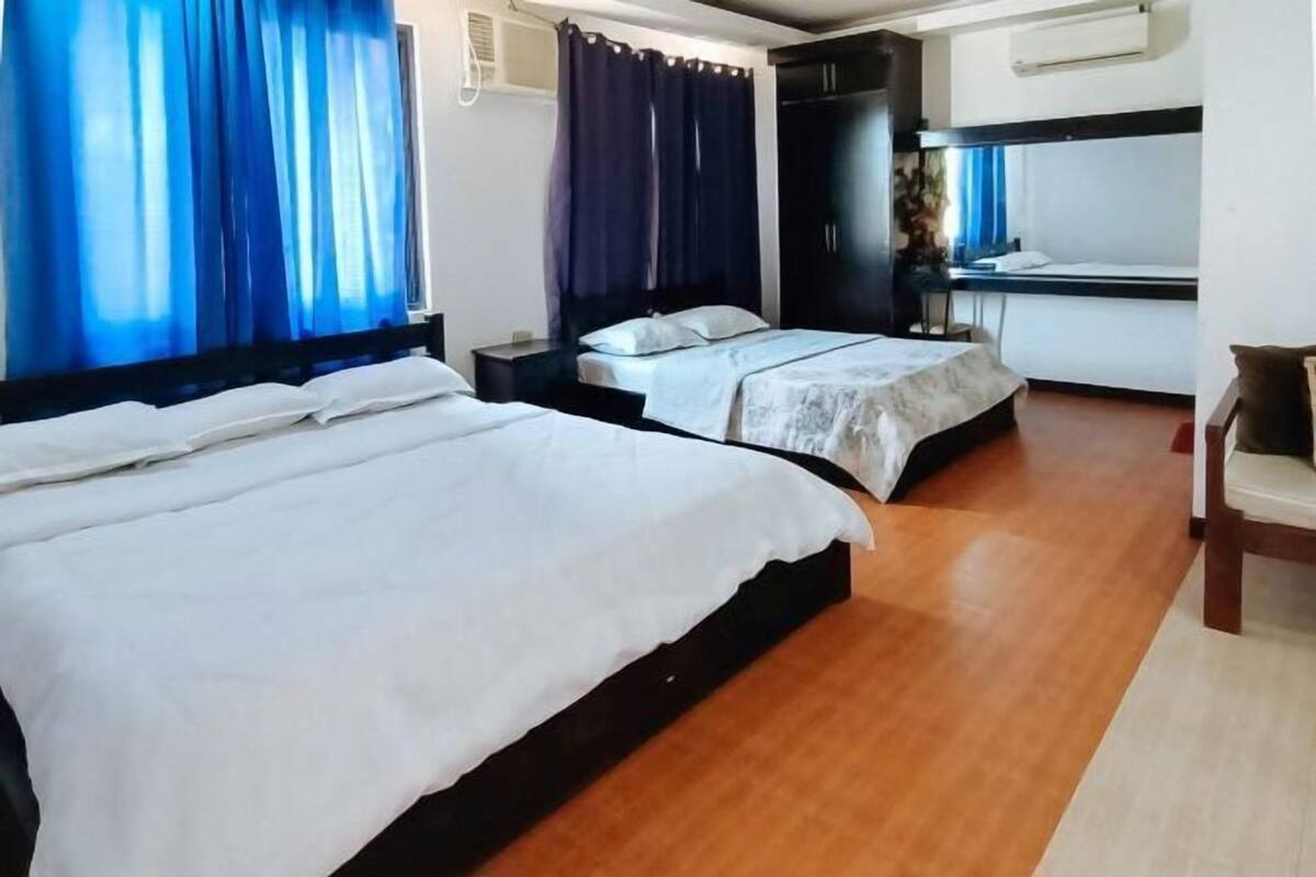 Une chambre d’hôtel avec deux lits, un bureau, une chaise et une armoire.