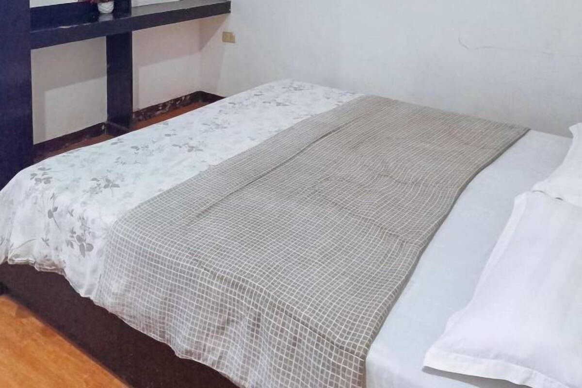 Un lit simple avec une couvre-lit à motifs floraux et une couverture à texture.