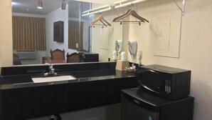 A bathroom with a black sink, a mirror, a microwave, and a small refrigerator. - Sierra Inn (South el Monte)
