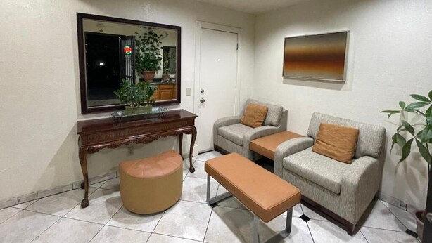 A living room with a sofa, ottoman, bench, and a desk with a mirror. - Sierra Inn (South el Monte)