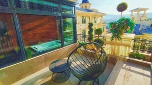 A balcony with a chair, a small table, and a view of a building with a blue roof. - Tianqing Hot Spring Hotel (Lanzhou)