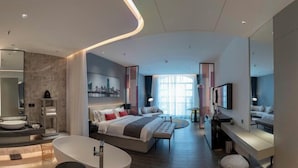 A modern hotel room with a large bed, a separate sitting area, a bathtub, and a television. - Tianqing Hot Spring Hotel (Lanzhou)