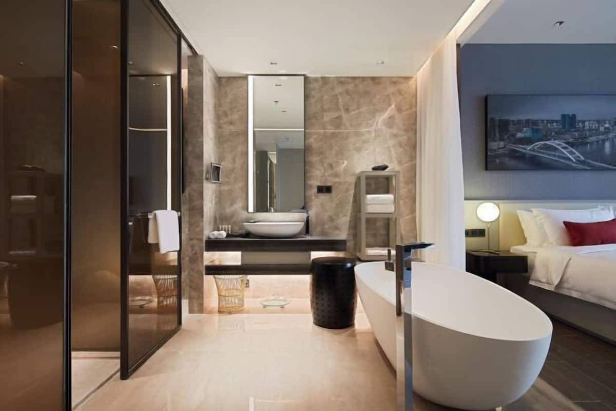 Un baño moderno con una bañera independiente, un espejo grande y un tocador con lavamanos.