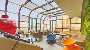 A modern interior with a glass ceiling, comfortable seating, and a view of the city. - Tianqing Hot Spring Hotel (Lanzhou)