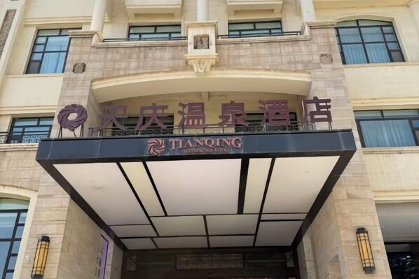A hotel entrance with a sign that reads 'TIANQING HOTEL' and a logo above it.