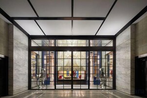A spacious lobby with a high ceiling, large glass doors, and a view of a colorful interior.